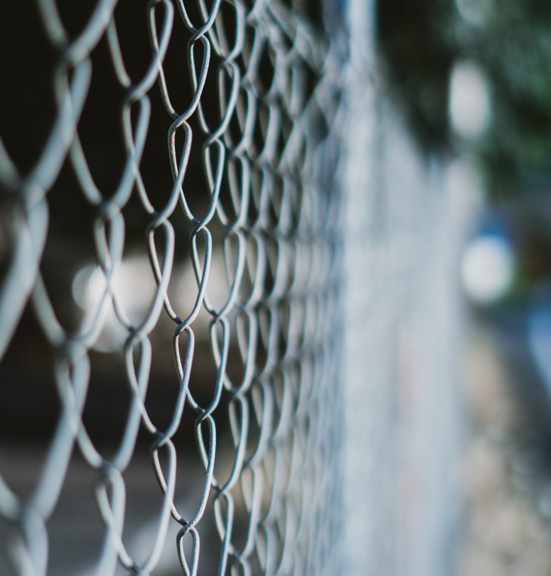 A vertical shot of a wired fence with a blurred background